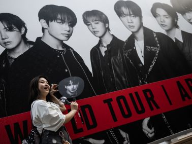 A BTS fan poses in front of a poster