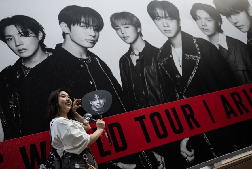 A BTS fan poses in front of a poster